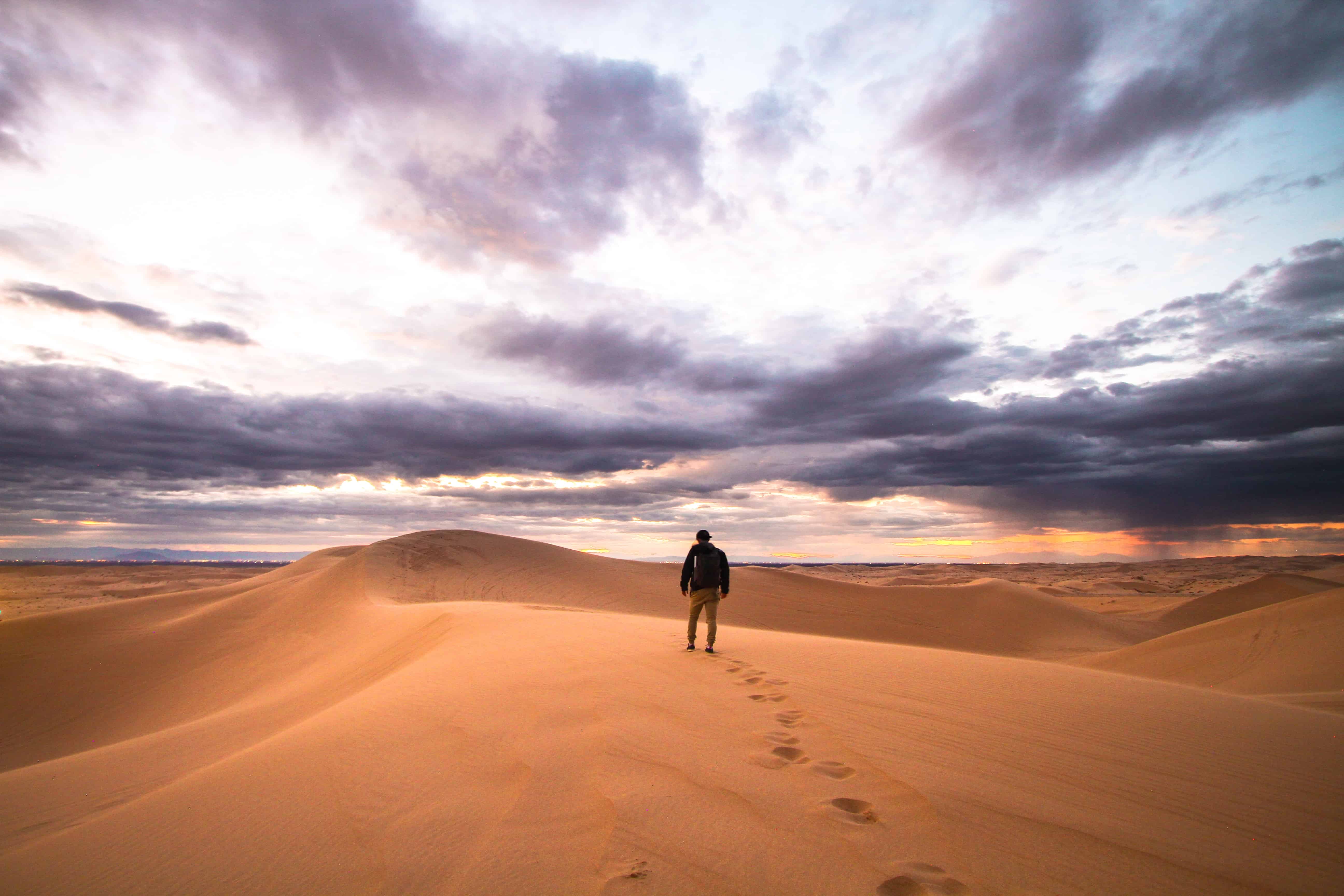 Man walking the desert, footprints being left behind.